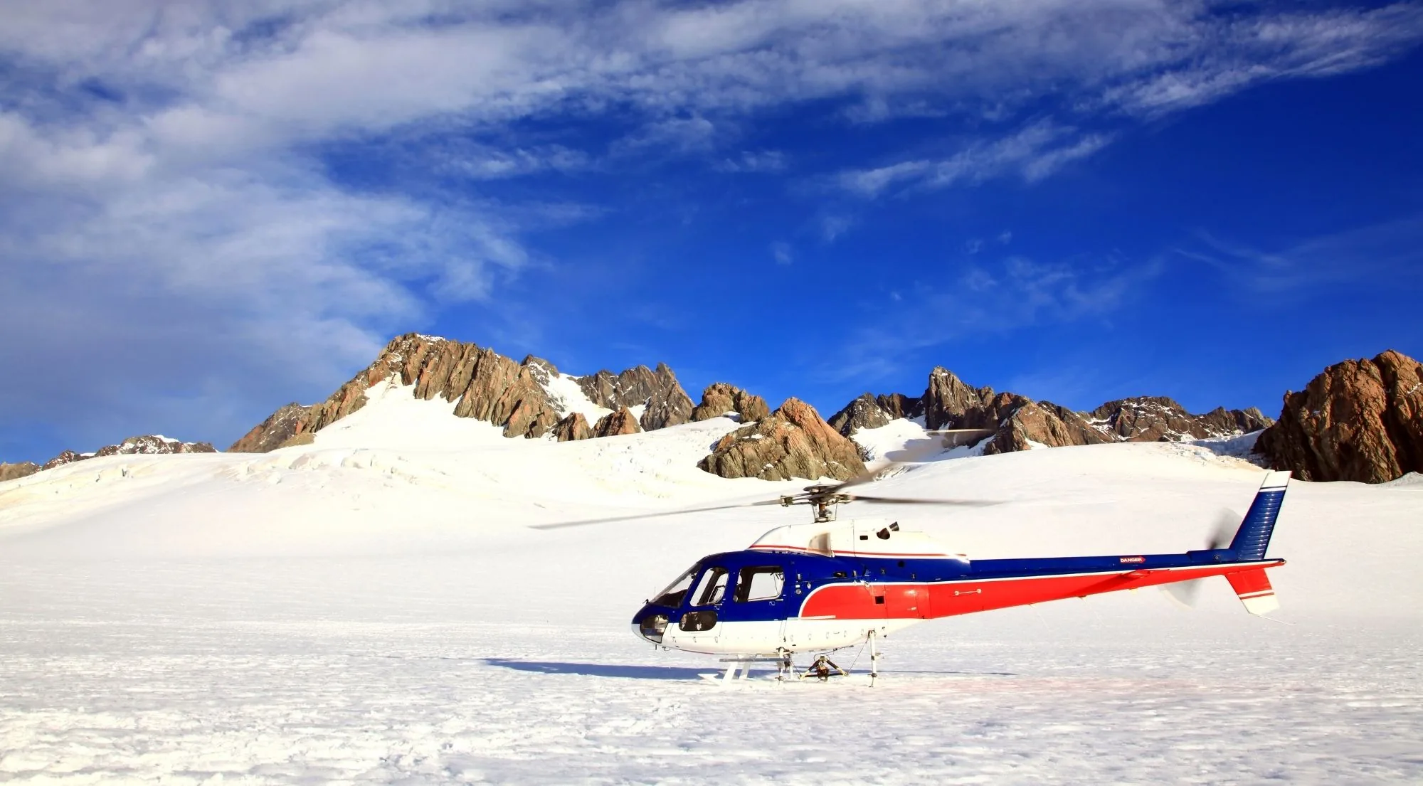A helicopter parked on a snowfield high in the Southern Alps