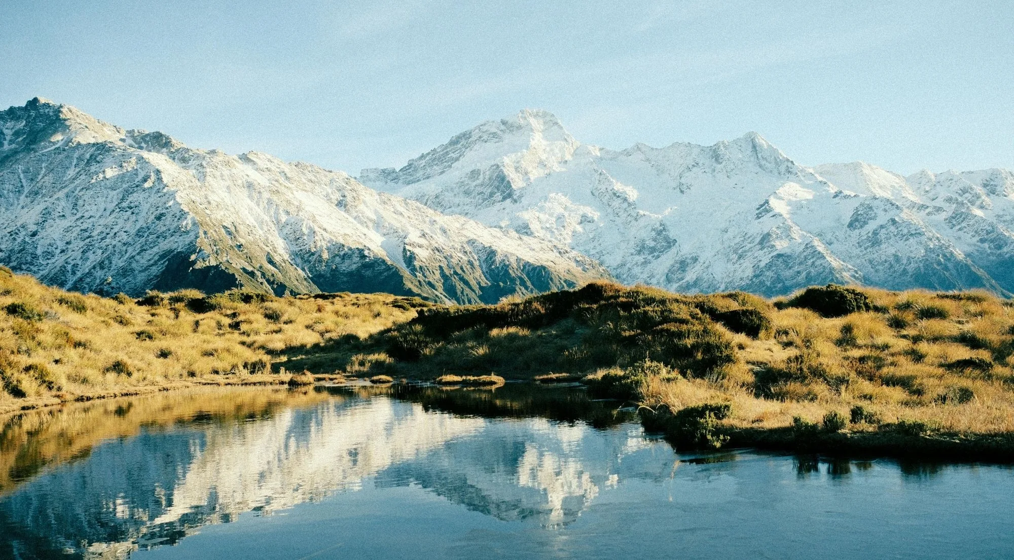 Snow-covered Southern Alps peaks reflected in an alpine tarn