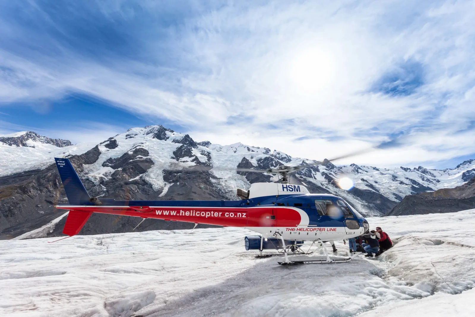 The Helicopter Line helicopter parked on the Tasman Glacier with snowy peaks behind