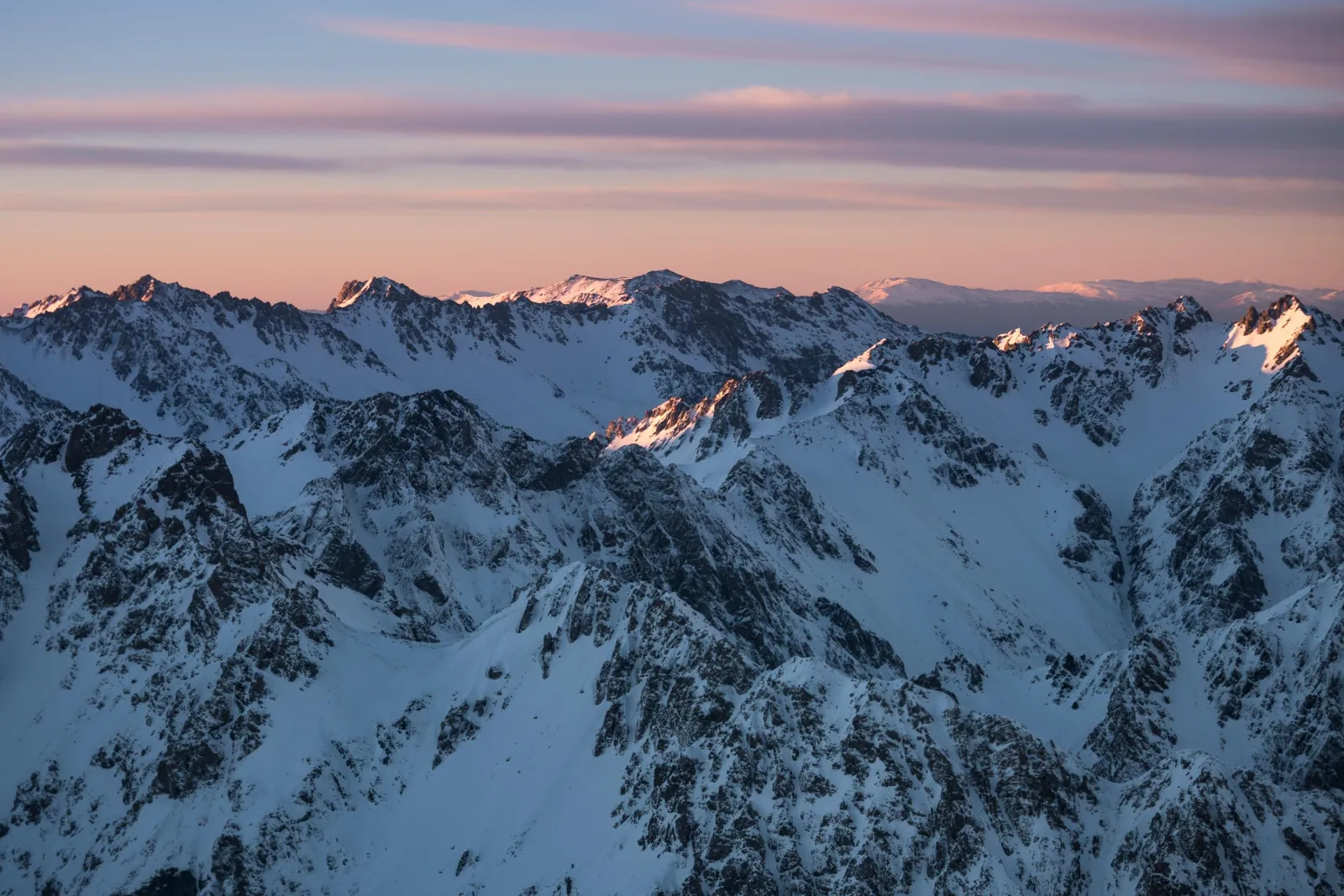 Snow-covered Southern Alps peaks under a pink evening sky
