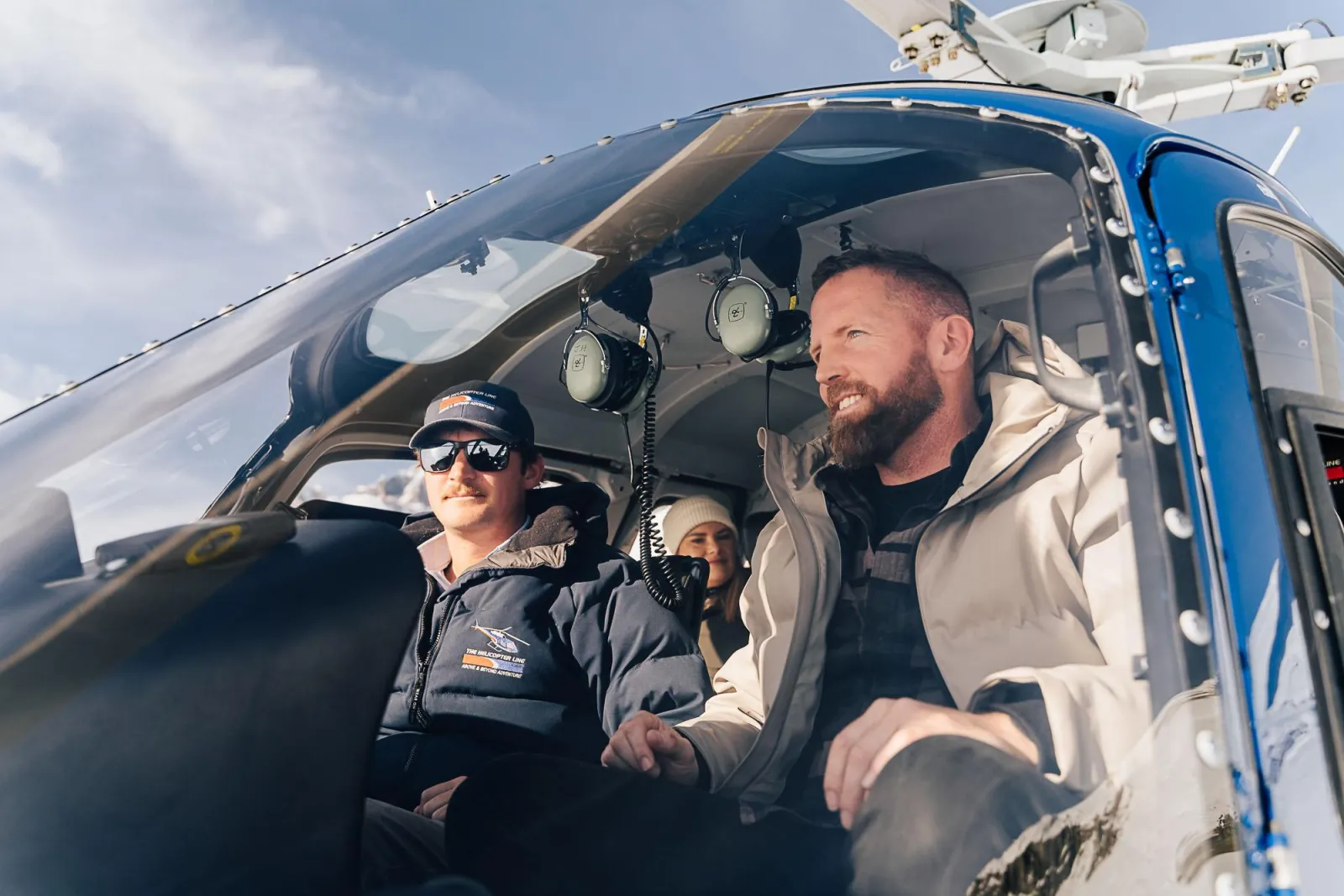 Pilot and passenger smiling in the front seats of the helicopter