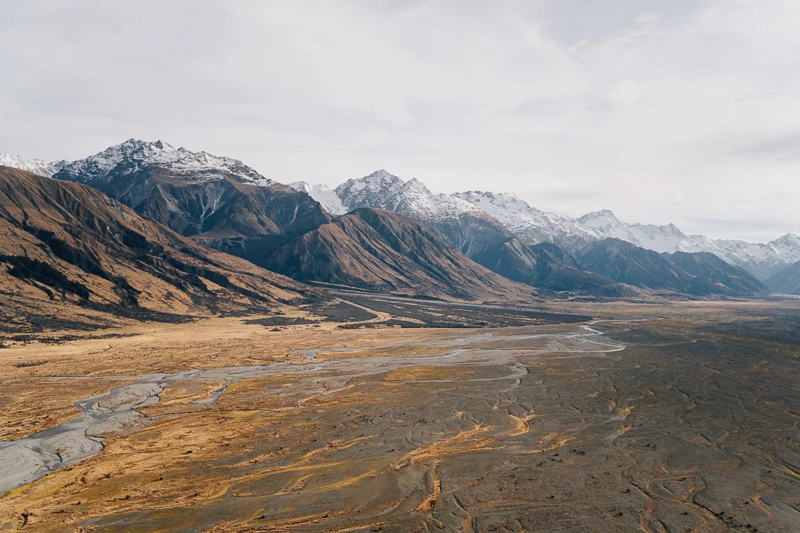 Braided riverbed and brown high-country hills below the Southern Alps