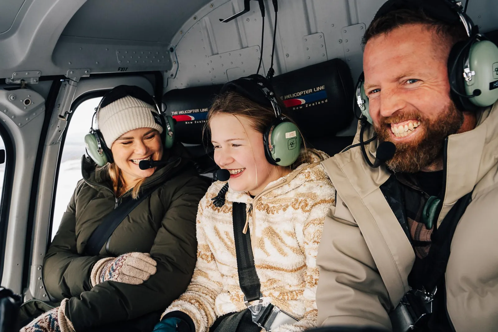 Family in headsets smiling in the back of the helicopter