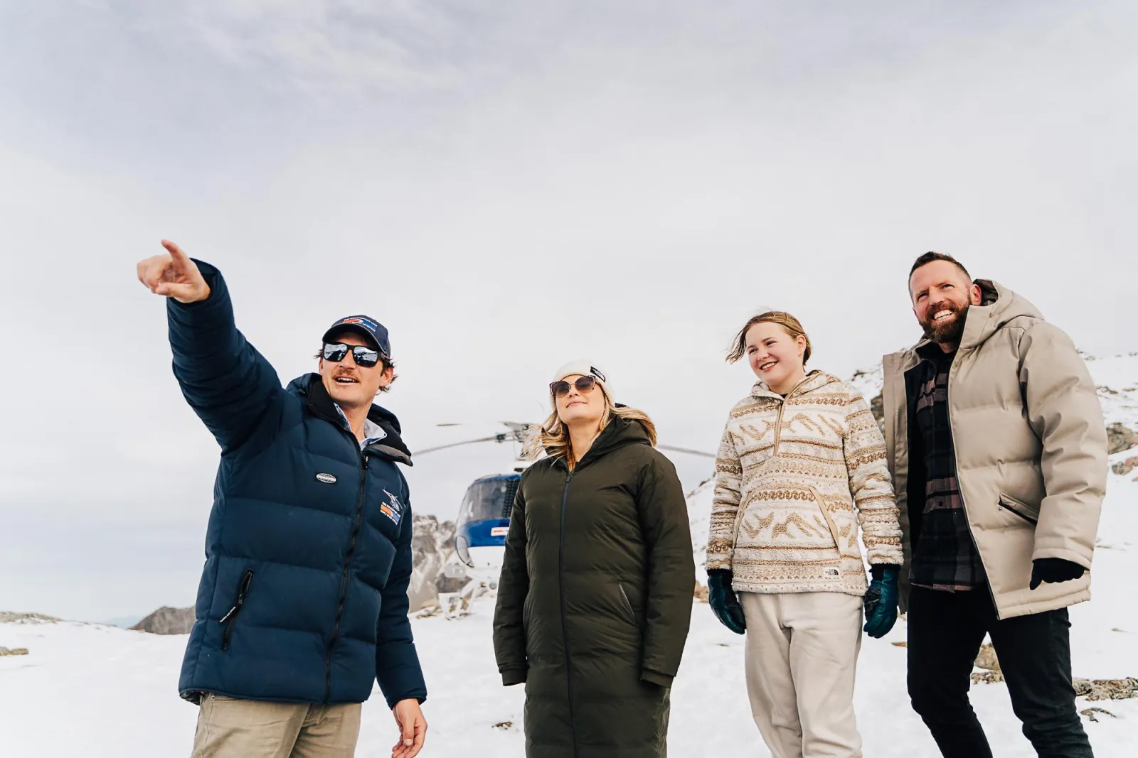 Pilot pointing out peaks to three passengers on a snow landing