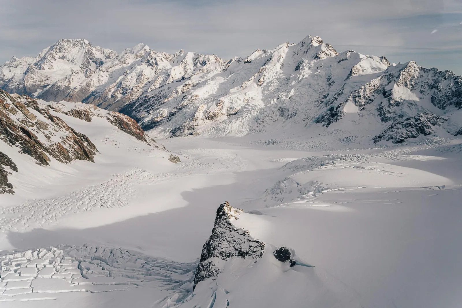 Wide glacier snowfields beneath a line of high peaks