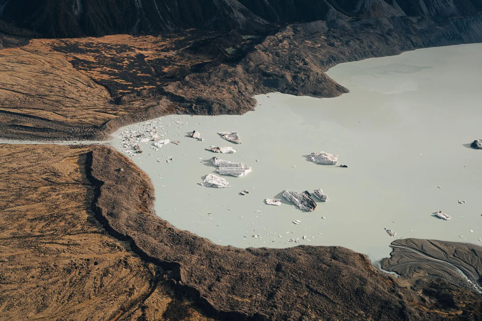 Icebergs floating in a milky glacial lake, seen from above