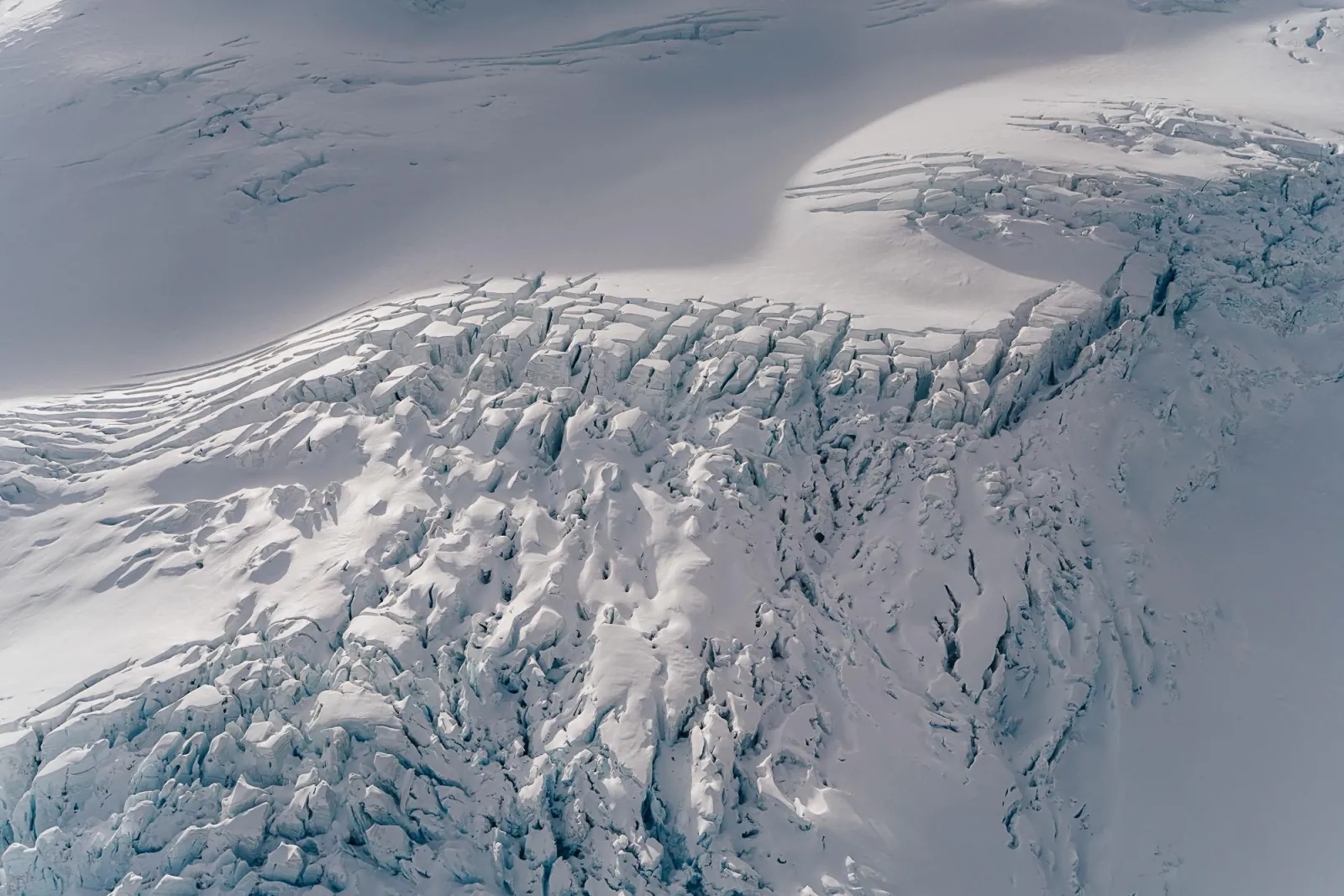 Close aerial view of crevasses breaking up a glacier's surface