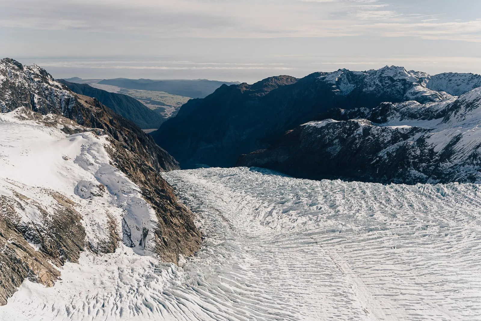 Glacier icefall descending toward the forested West Coast