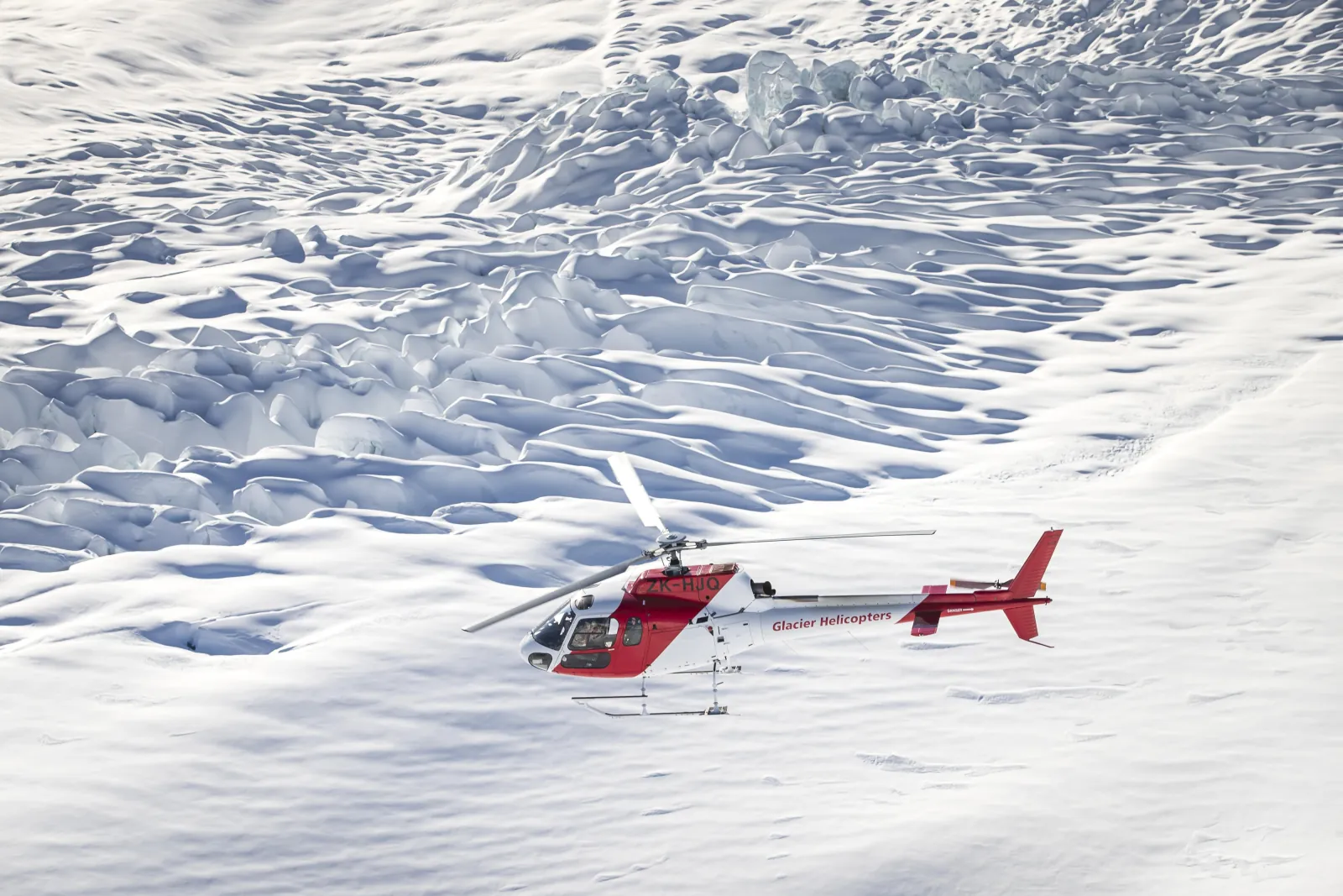 Glacier Helicopters helicopter landed on snow among glacier crevasses