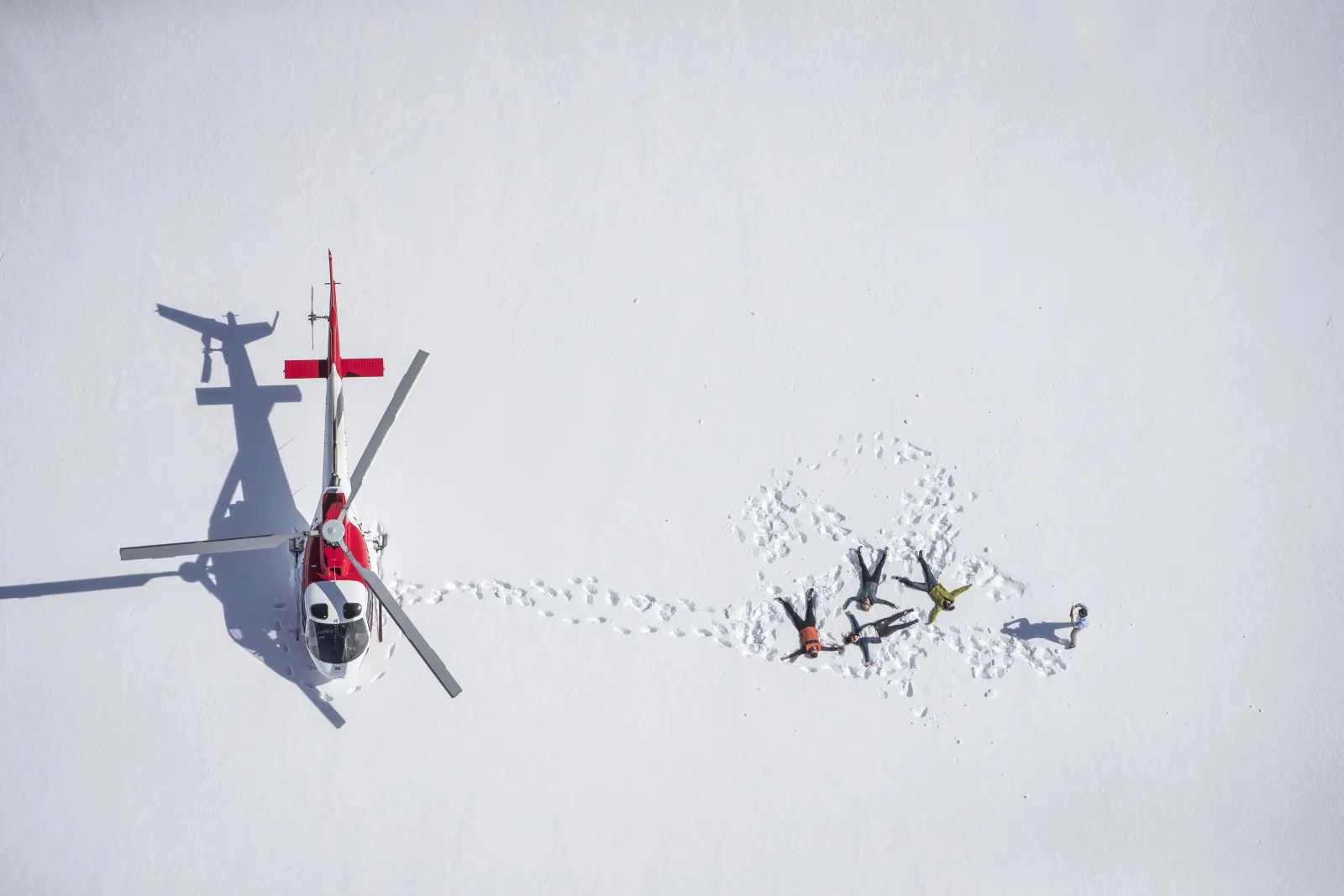 Overhead view of the helicopter and passengers making snow angels on the glacier
